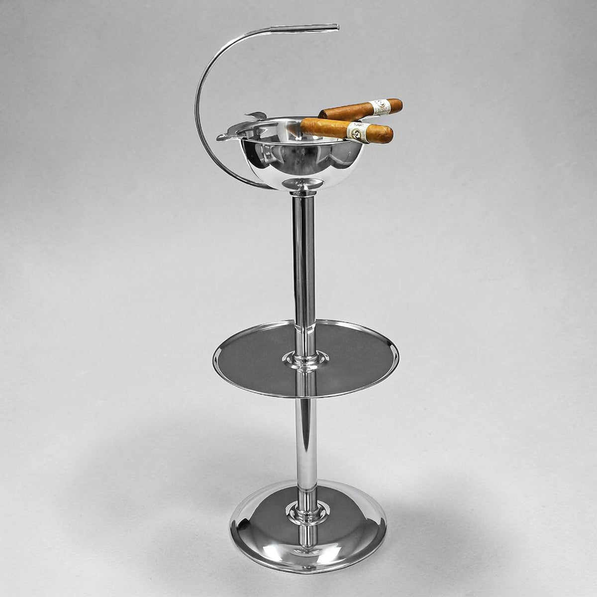 Stainless steel floor-standing cigar ashtray with a built-in accessory tray, four cigar rests, and two cigars resting in them. 