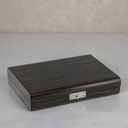 Wooden travel humidor with a metallic lock on a gray surface