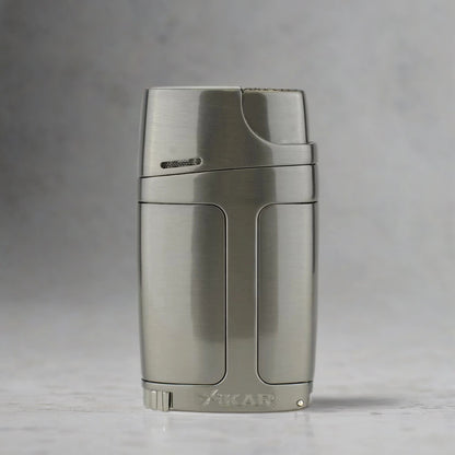 Metallic cigar torch lighter and punch with 'Xikar' branding on a gray background