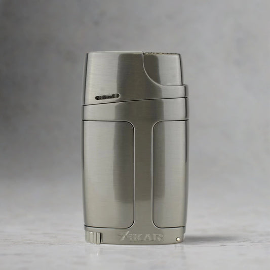 Metallic cigar torch lighter and punch with 'Xikar' branding on a gray background