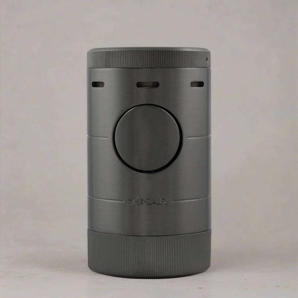 Tabletop cigar lighter with a gunmetal grey finish sitting flat on a neutral toned surface